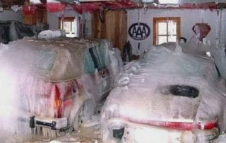 two cars in the garage frozen and covered in snow